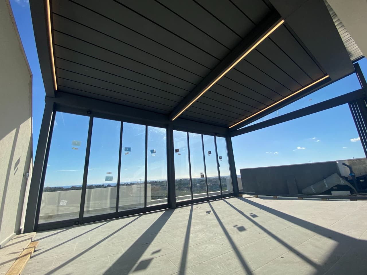 Glass enclosure with a louvered roof overlooking the sea