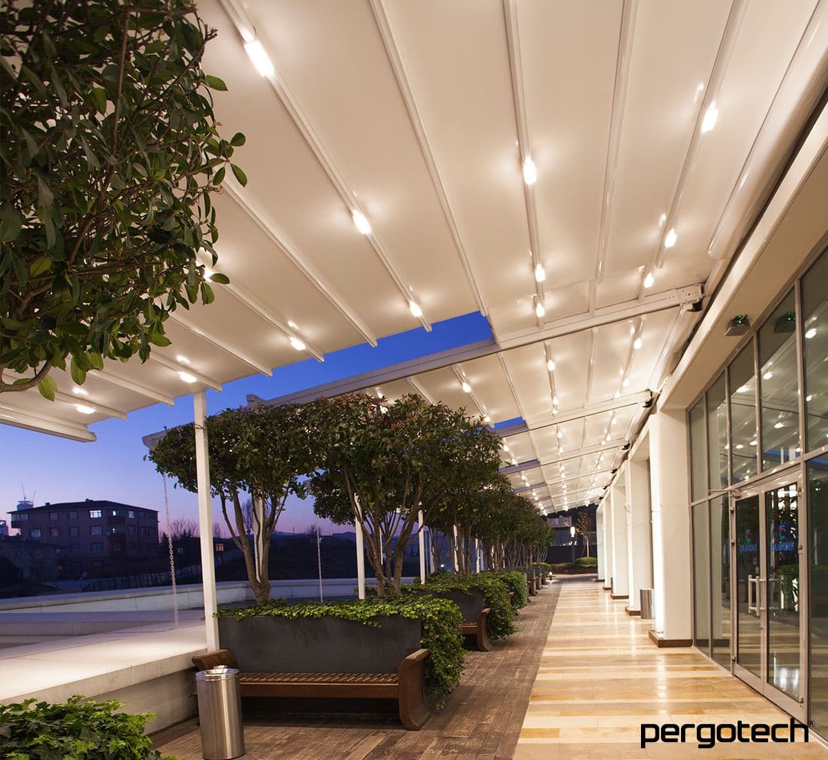 Illuminated retractable roof over a walkway at dusk